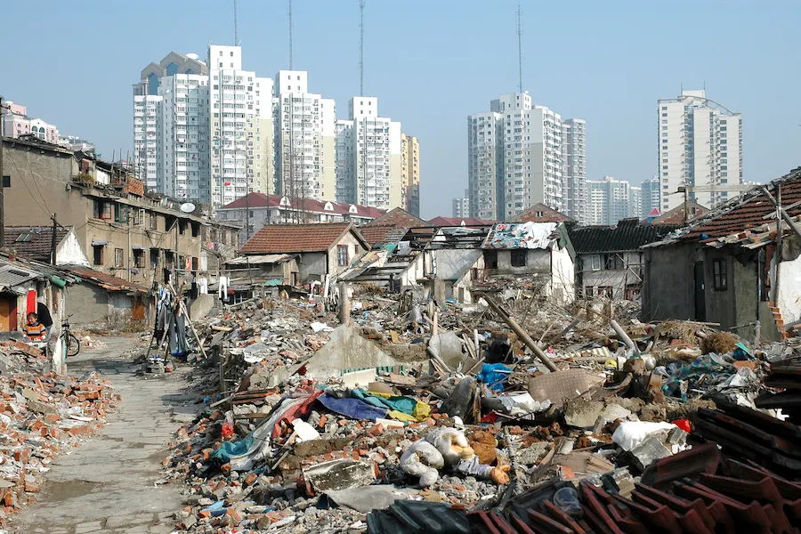Rubble of demolished houses in Shanghai with high-rise towers rising behind