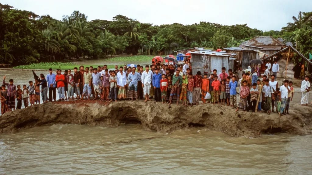 Villagers standing on an eroding riverbank in Bangladesh